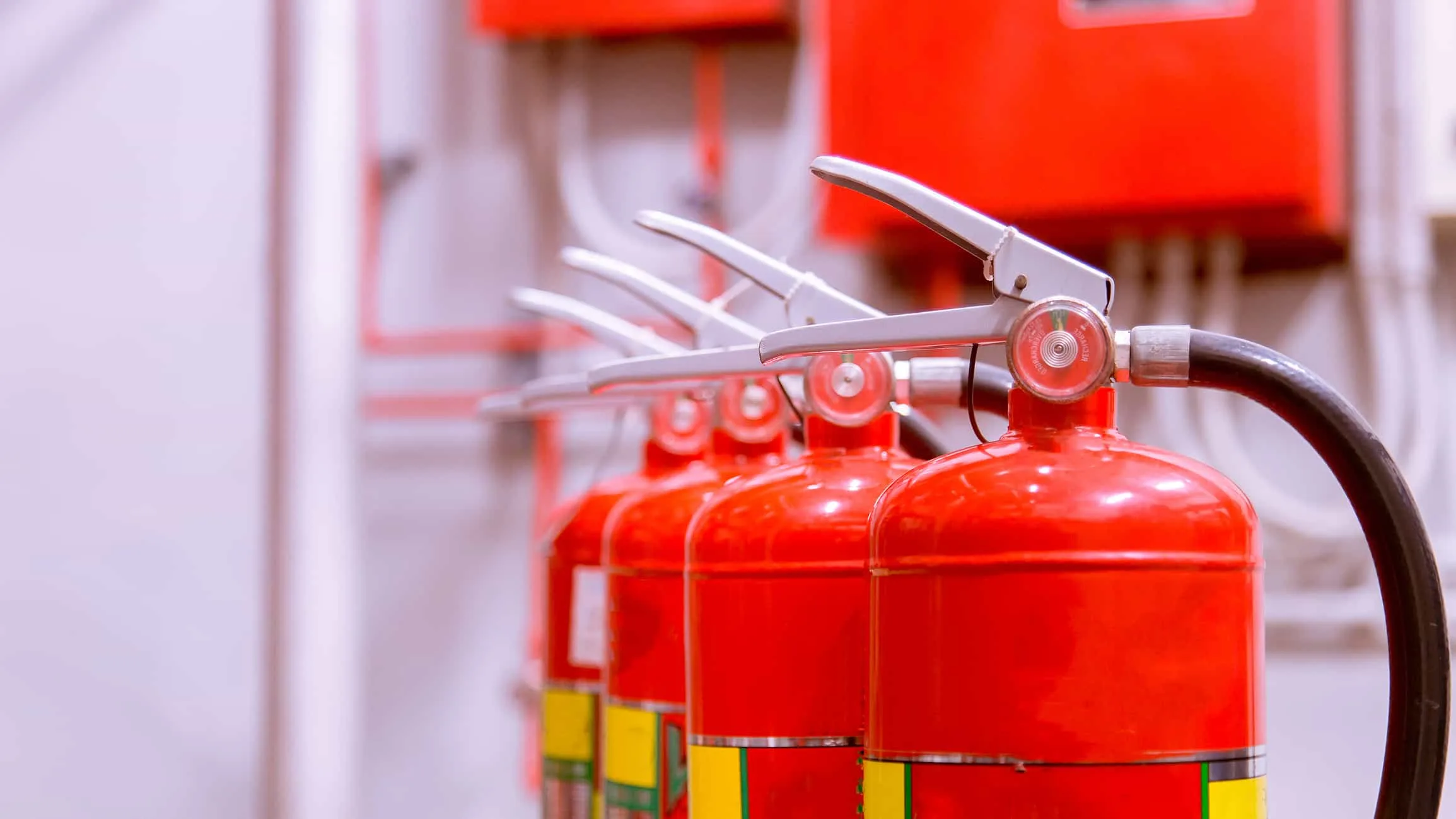 一位工程師正在檢查辦公室牆面上的消防設備，旁邊牆面掛有防火標示，呈現住家與商業空間消防安全的差異。 - 消防工程 | 消防設備安裝與智慧消防服務 | 焰控科技 - 消防工程 | 消防設備安裝與智慧消防服務 | 焰控科技